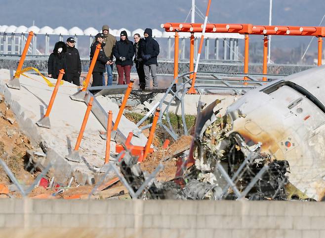 지난해 말 무안공항 사고현장에서 미국 NTSB와 보잉사, 국토부 사조위 관계자들이 로컬라이저 둔덕에 올라 사고기체를 살피고 있다. 연합뉴스