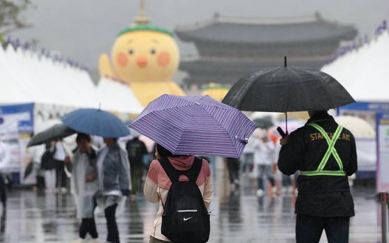Pedestrians walk by Gwanghwamun Square in central Seoul with umbrellas as rain poured down in Korea on April 19. [YONHAP]
