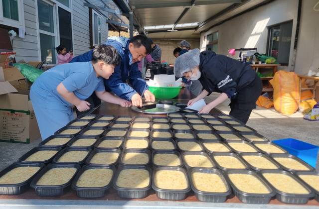 봉사자들이 전복죽을 용기에 담는 모습.