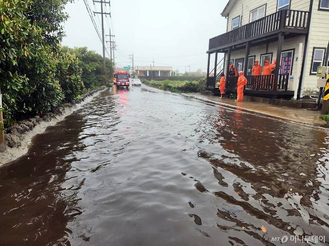 [제주=뉴시스] 강풍을 동반한 많은 비가 내리고 있는 22일 오전 제주 서귀포시 성산읍 한 도로가 침수돼 소방당국이 배수 지원에 나서고 있다. (사진=제주소방안전본부 제공)