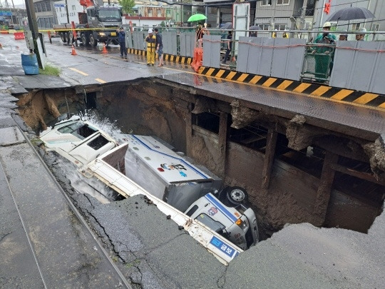 지난해 9월 부산 사상구 도로에서 배수 지원 차량과 5t 트럭이 싱크홀에 빠졌다. 부산소방재난본부 제공