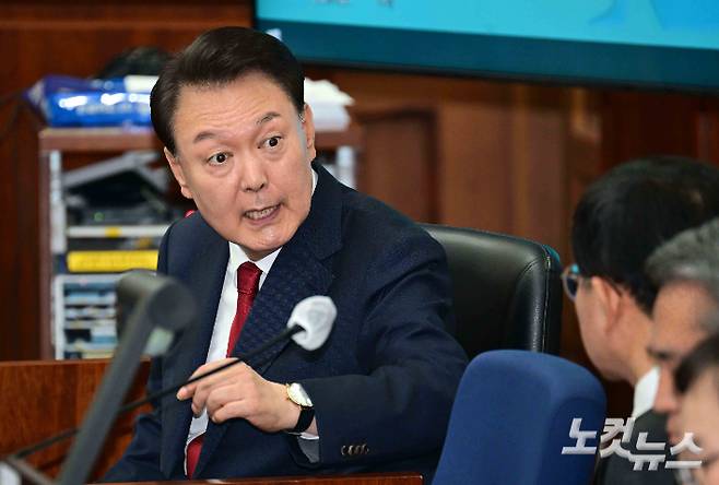 12·3 비상계엄을 선포해 내란 우두머리 혐의로 재판에 넘겨진 윤석열 전 대통령이 21일 오전 서울 서초구 서울중앙지법 417호 법정에 앉아 변호인단과 대화를 하고 있다. 사진공동취재단