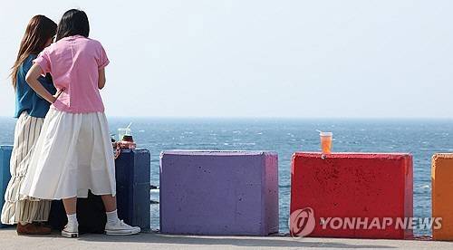 제주에서 유명한 무지개도로를 찾은 외국인 관광객이 바다 정취를 즐기고 있다.<연합뉴스>