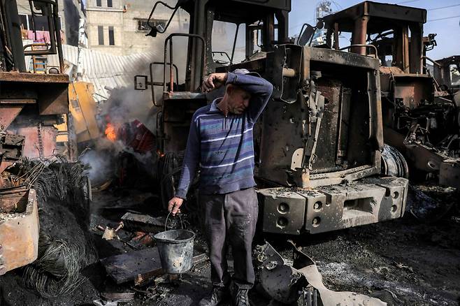 희망을 꿈꿀 수 있을까 22일(현지시간) 팔레스타인 가자지구 북부 자발리야에서 한 시민이 이스라엘의 폭격으로 불타버린 굴착기 옆에서 소매로 이마의 땀을 닦고 있다. AFP연합뉴스