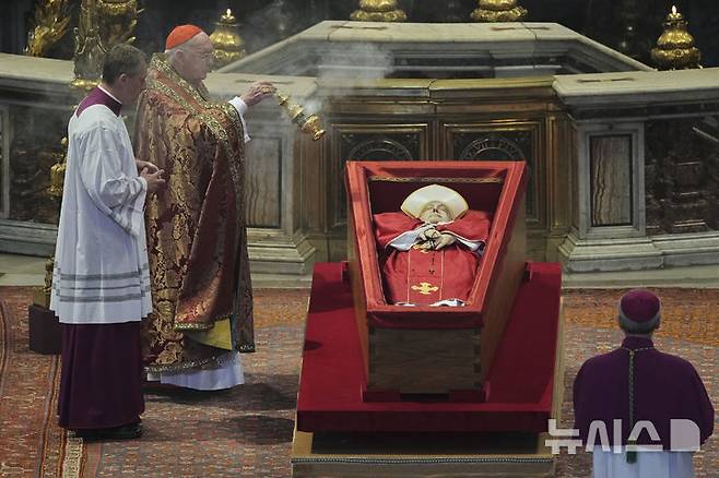 [바티칸시국=AP/뉴시스] 23일(현지 시간) 바티칸의 성 베드로 대성당에서 궁무처장 케빈 조셉 패럴 추기경이 프란치스코 교황의 시신 주위에 향을 뿌리고 있다. 프란치스코 교황의 시신은 사흘간 대성당에 안치돼 일반 신자들의 조문을 받는다. 2025.04.23.