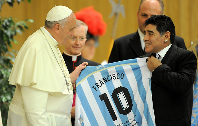 프란치스코 교황이 2014년 9월 이탈리아 로마 바티칸에서 열린 ‘종교 간 평화의 경기’ 선수단 접견 행사에서 아르헨티나 축구 영웅 디에고 마라도나로부터 배번 10번과 자신의 이름이 적힌 유니폼을 전달받고 있다. 게티이미지