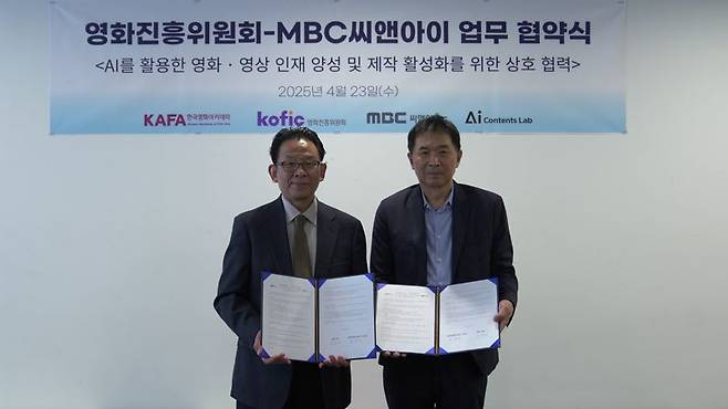 지난 23일 일산 MBC 드림센터에서 ‘AI 영상 인재양성·제작 활성화 협약식’이 열린 가운데 한상준 영화진흥위원장(왼쪽)과 도인태 MBC C&I 대표가 협약서를 들고 기념촬영하고 있다. 영화진흥위원회 제공