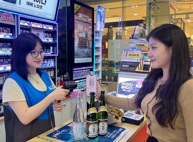 GS25를 찾은 한 고객이 일본 사케와 중국 바이주 제품을 구매하고 있다.  [GS리테일 제공]