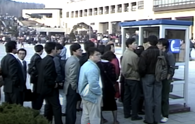 1987년 서울의 한 대학 원서 접수장 인근에 있는 공중전화 부스 앞에 학생들과 학부모들이 줄지어 대기하고 있다. 유튜브 ‘KBS 옛날티비’ 캡처.