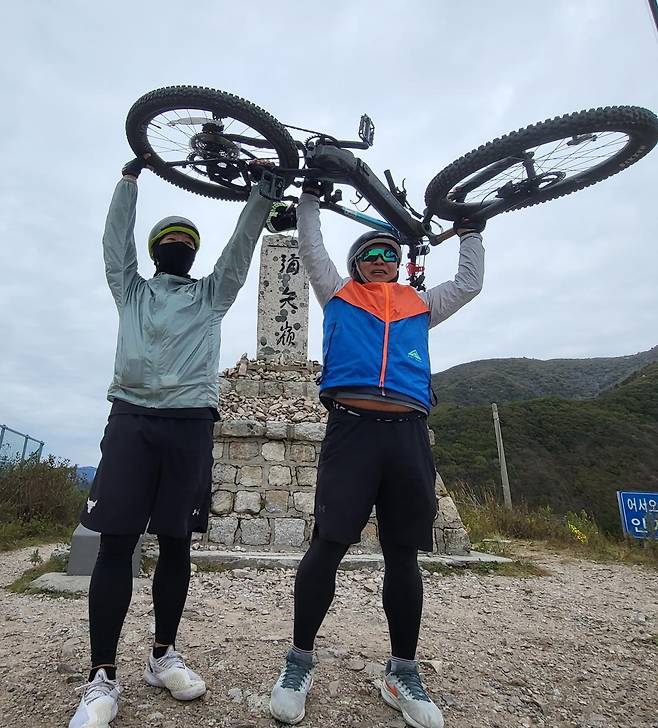 전우호 메이트네트웍스 대표(오른쪽)가 2022년 아들과 자전거를 타고 대한민국 한바퀴를 돌다 대관령 미시령에서 자전거를 들어보이고 있다. 전우호 대표 제공.