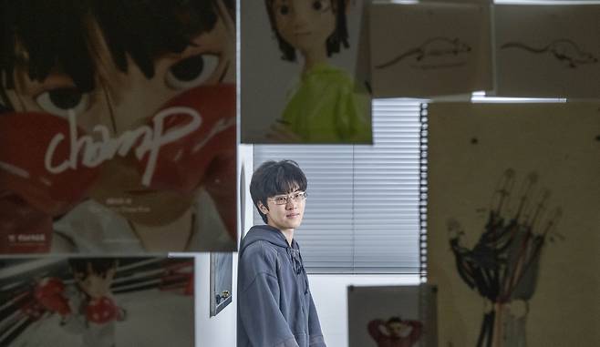 Kim Onew, a 3D visual effects artist, poses for a photo in front of the poster and concept sketches for his short film "Champ," ahead of an interview with The Korea Herald at Aedia Studio in Seoul on March 27. (Im Se-jun/The Korea Herald)