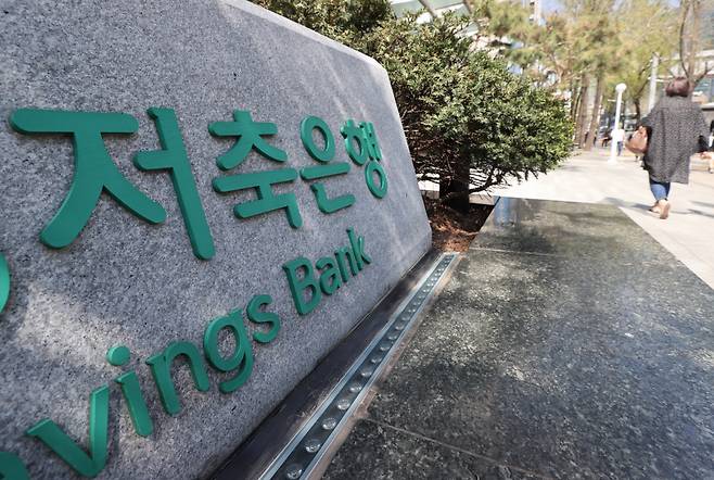 한국금융연구원은 27일 발표한 보고서를 통해 "대형과 중소형 저축은행 간 양극화 현상을 고려해 규제 체계를 차등화해야 한다"고 밝혔다. 사진은 서울의 한 저축은행 안내판 앞으로 시민이 지나가는 모습 ⓒ연합뉴스