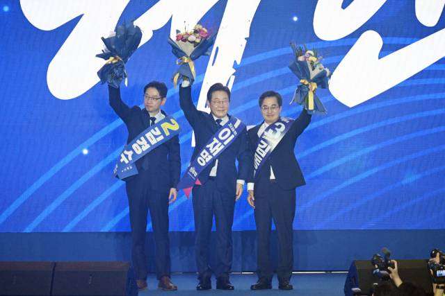 이재명(가운데) 더불어민주당 대선 후보가 27일 경기 고양시 킨텍스에서 민주당 대선 후보로 선출된 후 김경수(왼쪽), 김동연 예비후보와 함께 당원들을 향해 손을 흔들고 있다. 조태형 기자