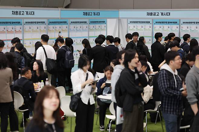 지난 23일 서울 강남구 코엑스에서 열린 2025 중견기업 일자리 박람회를 찾은 구직자들이 채용공고 게시물을 보고 있다. ⓒ연합뉴스