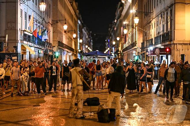 이베리아 반도에 대규모 정전이 발생한 가운데 28일(현지시간) 포르투갈 리스본 루아 아우구스타 거리에 조명이 복원되자 거리 예술가들이 연주를 하고 있다. ⓒ AFP=뉴스1