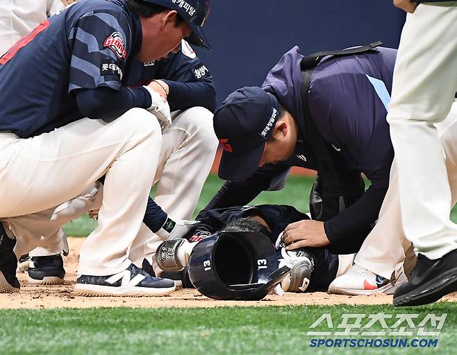 쓰러진 전민재를 살피는 트레이너와 코치들