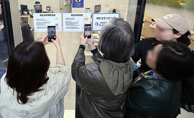 SK텔레콤 가입자 유심(USIM) 정보 해킹 사고 관련 유심 무료교체 서비스 이틀 째인 29일 오전 서울 종로구 T월드 직영 매장 앞에서 번호표를 받지 못한 고객들이 온라인 예약을 하고 있다./뉴스1