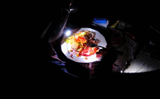 호세 마리아 카사이스(72)가 28일 스페인 바르셀로나 자택에서 배터리가 달린 휴대용 산소발생기 배낭을 메고 숨을 쉬면서 손전등을 이용해 식사를 하고 있다. 로이터=연합뉴스