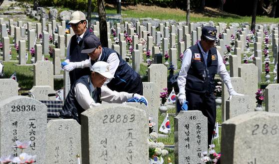 National merit recipients clean gravestones at the Seoul National Cemetery in Songpa District, southern Seoul, on June 3, 2024. [NEWS1]