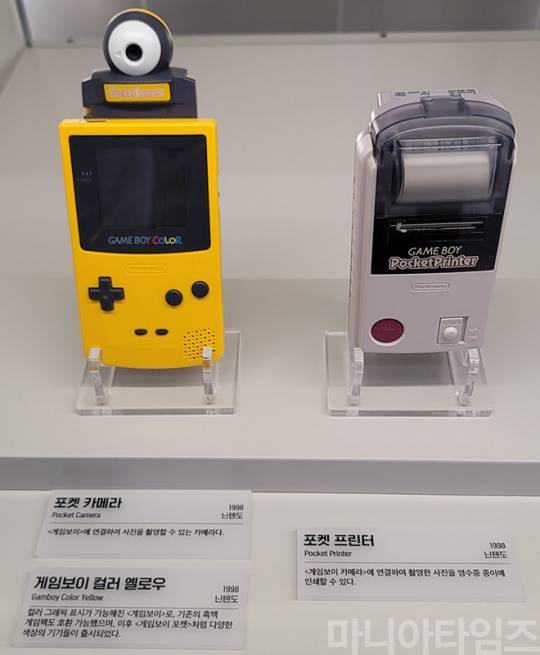 넷마블게임박물관. 닌텐도의 '게임보이 컬러'의 옐로우 버전(1998년, 왼쪽)와 게임보이 컬러용 '포켓 카메라'(1998년, 게임보이 컬러의 위에 장착돼 있다), '포켓 프린터'(1998년, 오른쪽). 포켓 프린터는 포켓 카메라와 연결하면 영수증용 종이와 같은 것에 인쇄가 가능했다. 촬영 : 이동근 기자