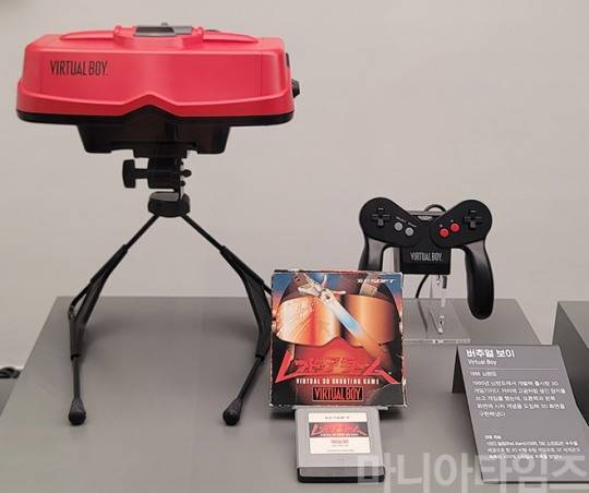 넷마블게임박물관. 1995년 발매된 닌텐도의 3D 게임기 '버추얼 보이'. TV에 연결하는 것이 아니고 기기 내부에 화면이 있다. 스테레오스코피 기술을 사용해 내부에는 3D화면이 보인다. 실제 사용시에는 삼각대 같은 스탠드에 올려놓고 얼굴을 들이대고 사용했다고 한다.  닌텐도가 최초로 32비트 프로세서를 탑재해 성능은 나쁘지 않았다. 문제는 적색 LED만 사용해 화면은 붉은색으로만 표기됐기 때문에 눈에 가해지는 피로도가 상당했고, 닌텐도의 최고 실패작 중 하나로 꼽힌다. 전 세계 판매량은 약 77만 대. 아래 패키지는 몇 안되는 버추얼 보이용 게임인 T&E소프트의 3D 비행 슈팅 게임 '레드 알람'. 촬영 : 이동근 기자