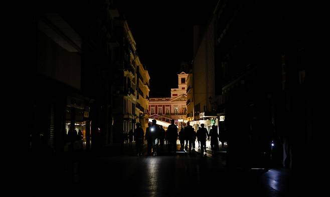 28일(현지시간) 스페인·포르투갈·프랑스 등 유럽 남서부 일대에 대규모 정전 사태가 발생해 주요 도시들이 암흑에 휩싸인 가운데 스페인 마드리드 도심에 사람들이 휴대전화 플래시를 손전등 대용으로 삼아 어두운 길을 비추며 걷고 있다. 마드리드=로이터연합뉴스