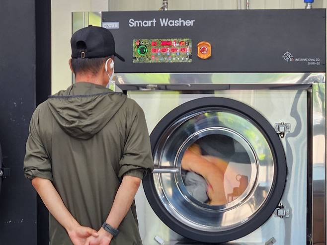 28일 노동자 작업복 세탁기가 돌아가는 모습을 지켜보고 있는 세탁소 근로자 모습 (사진=정바름 기자)