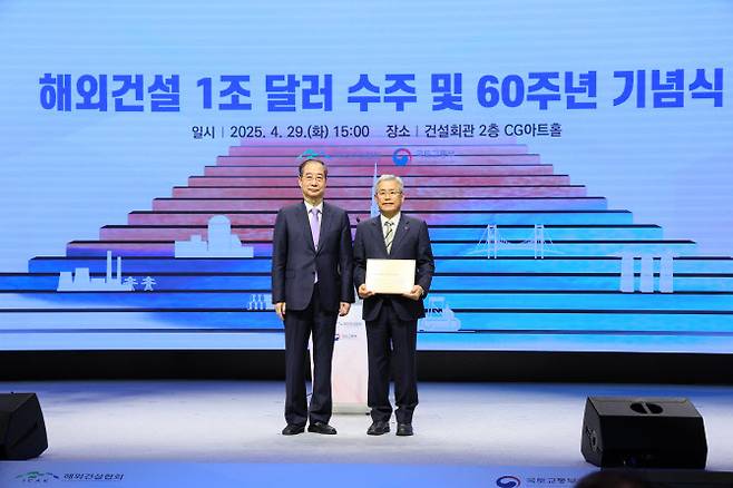 한덕수(왼쪽) 대통령 권한대행 국무총리가 지난 29일 해외건설협회의 해외건설 60주년·1조달러 달성 기념식에서 김동철 한국전력공사 사장에게 대통령 기념패를 수여 후 기념촬영하고 있다. 한전의 아랍에미리트(UAE) 바라카 원전사업은 이날 해외건설 10대 프로젝트로 선정되며 명예의 전당에 헌정됐다. (사진=한전)