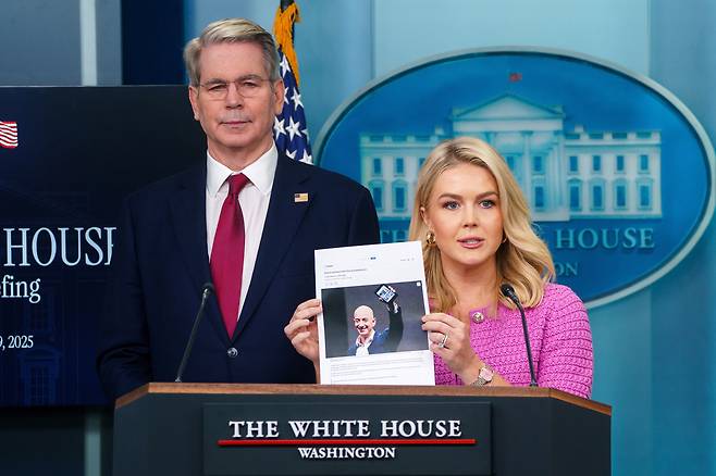 캐롤라인 레빗 백악관 대변인(가운데)이 29일 미국 워싱턴 DC 백악관에서 기자 브리핑 중 스콧 베센트 미 재무장관(왼쪽)과 함께 아마존 창립자 제프 베조스 사진을 들고 있다. /연합뉴스