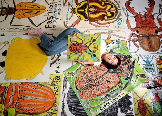 김유대 작가가 국내에서 가장 큰 판형으로 펴낸 자신의 그림책 '이런, 멋쟁이들!'을 들어보이고 있다. A0용지 2장을 이어붙인 화판 위에 몸길이 0.2~15㎝인 딱정벌레목 곤충을 크게 그린 그림이 바닥에 깔려있다. 왕태석 선임기자