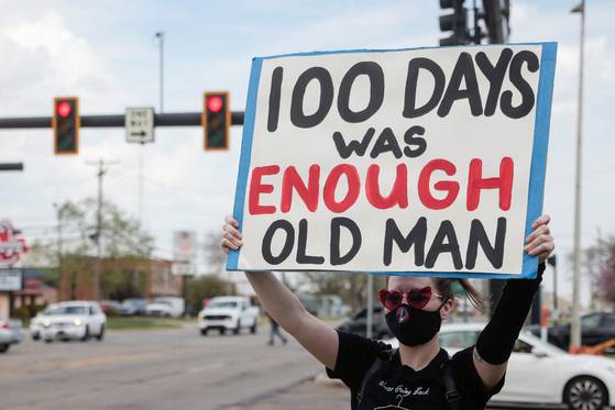 29일(현지시간) 도널드 트럼프 미국 대통령의 취임 100일 기념 집회가 열린 미시간주 머컴 카운티 행사장 밖에서 한 시민이 트럼프 대통령에 반대하는 내용의 피켓을 들며 시위하고 있다. 로이터=연합뉴스