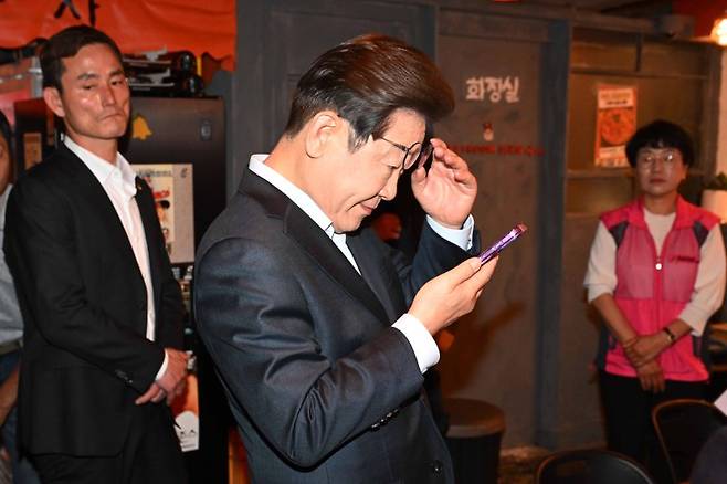 더불어민주당 이재명 대선 후보가 1일 서울 종로구의 한 포차 식당에서 '당신의 하루를 만드는, 보이지 않는 영웅들'이란 주제로 배달 라이더, 택배 기사 등 비(非)전형 노동자들과 간담회를 마친 뒤 휴대전화를 확인하고 있다. 사진=연합뉴스