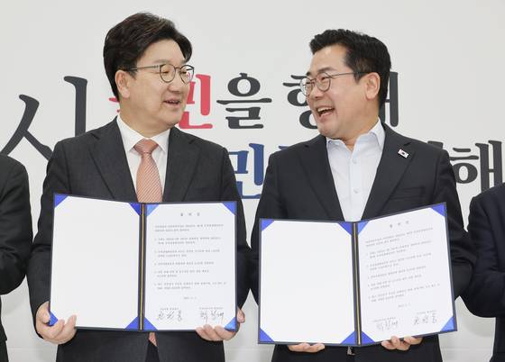 Democratic Party floor leader Park Chan-dae, right, and People Power Party floor leader Kweon Seong-dong smile after signing an agreement on the supplementary budget at the National Assembly in western Seoul on May 1. [YONHAP]