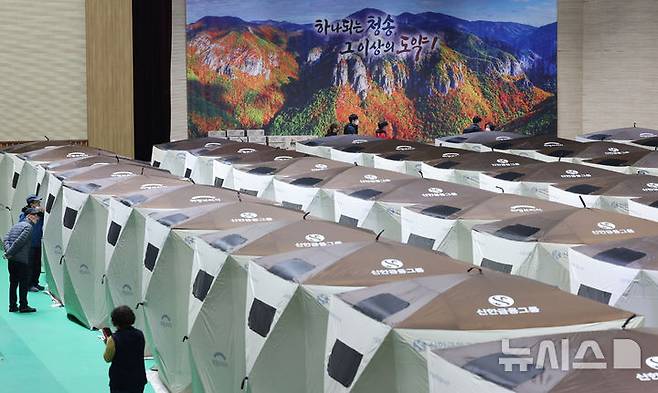 [청송=뉴시스] 김금보 기자 = 경북 청송군 청송국민체육센터에 마련된 산불 대피소 이재민 텐트 뒤로 산불피해를 입기전 주왕산 사진이 보이고 있다. 2025.03.28. kgb@newsis.com