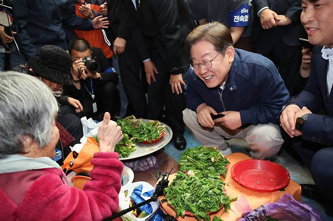 더불어민주당 이재명 대선 후보가 '골목골목 경청투어' 접경지역 방문 이틀째인 2일 강원도 인제군 원통전통시장에서 엄나무순을 사며 어르신과 대화하고 있다. 연합뉴스