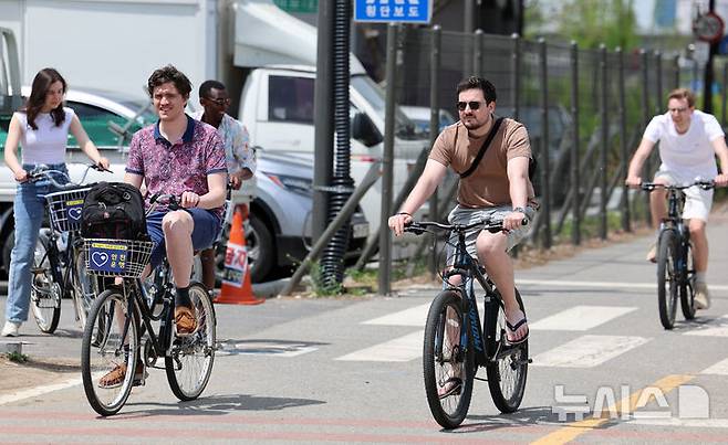 [서울=뉴시스] 이영환 기자 = 서울의 낮기온이 24도까지 오르며 초여름 날씨를 보인 23일 오후 서울 영등포구 여의도한강공원에서 반팔을 입은 외국인들이 자전거를 타고 있다. 2025.04.23. 20hwan@newsis.com