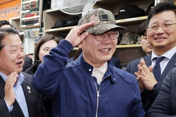 민심을 청취하는 ‘경청 투어’에 나선 이재명 더불어민주당 대선후보가 2일 오후 강원도 화천군 화천공영버스터미널 인근의 한 군장점에서 김병주 최고위원이 사준 병장 계급장이 달린 육군 모자를 써보고 있다. 뉴시스