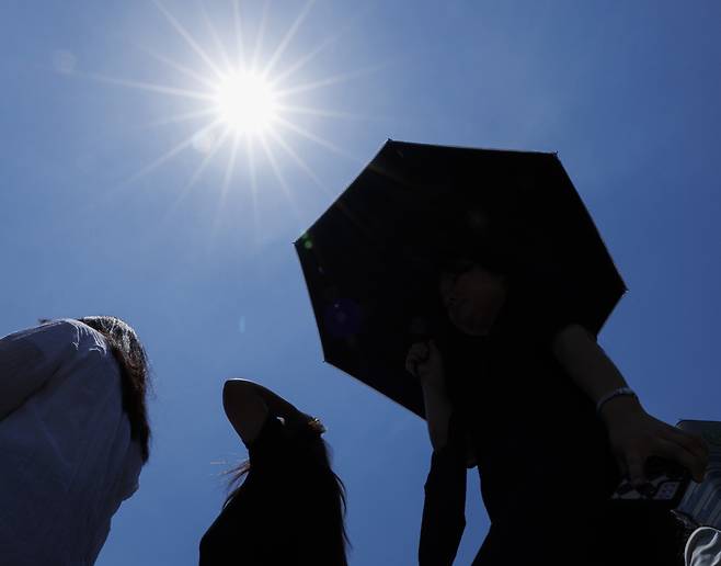 서울 광화문 건널목에서 시민들이 작열하는 태양 아래 이동하고 있다.   연합뉴스