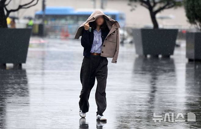 [서울=뉴시스] 김선웅 기자 = 수도권에 봄비가 내린 14일 서울 종로구 광화문광장에서 한 시민이 옷으로 비를 피하고 있다. 2025.04.14. mangusta@newsis.com