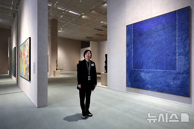 [서울=뉴시스] 박진희 기자 = 한국현대미술 하이라이트전시를 기획한 배명지 국립현대미술관 학예연구사가 김환기의 '산울림'(1973)작품앞에서 포즈를 취했다.  pak7130@newsis.com