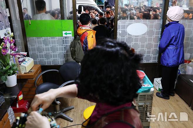 [양양=뉴시스] 조성우 기자 = 민심을 청취하는 '경청 투어'에 나선 이재명 더불어민주당 대선후보가 3일 강원도 양양군 양양시장에서 상인 및 주민들에게 인사를 하는 가운데 시장 내 한 미용실에서 상인과 고객들이 이 후보 쪽을 바라보고 있다. 2025.05.03. xconfind@newsis.com