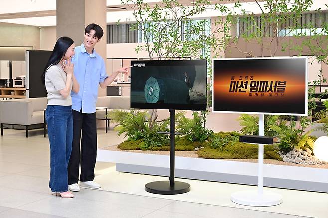삼성전자 모델이 2025년형 OLED TV, 더 프레임 TV와 결합된 무빙스타일에서 상영되는 '미션 임파서블 파이널 레코닝' 영상을 감상하고 있다.
