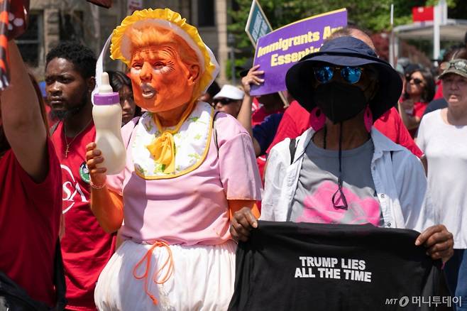 [워싱턴=AP/뉴시스] 1일(현지 시간) 미국 워싱턴에서 열린 노동절 시위 중 시위대가 도널드 트럼프 대통령을 아기로 묘사한 인형을 들고 행진하고 있다. 2025.05.02. /사진=민경찬