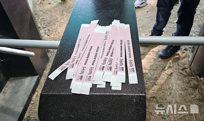 [제주=뉴시스] 임재영 기자 = 4일 오전 한라산국립공원 관음사탐방로 입구에서 탐방객에게 나눠주고 있는 '띠지'. 2025.05.04. ijy788@newsis.com