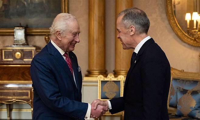 찰스 3세 영국 국왕(왼쪽)이 지난 3월17일 런던 버킹엄궁에서 영국을&nbsp;방문한 마크 카니 캐나다 총리와 만나 인사를 나누고 있다. 찰스 3세는 영국 국왕인 동시에 캐나다 국왕이기도 하다. AP연합뉴스