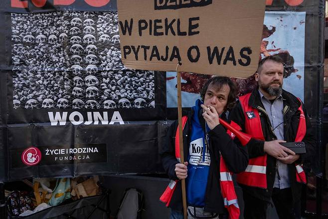 폴란드 바르샤바에 낙태 상담소가 개소한 다음 날인 지난 3월 8일(현지시간) 상담소 앞에서 열린 반낙태 시위에서 한 남성이 ‘지옥에서 당신을 찾고 있다’라고 적힌 팻말을 들고 있다. AFP연합뉴스