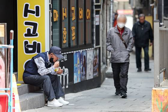 A senior citizen eats juk (Korean porridge) on the side of the road in Jongno District, central Seoul, on March 24. [NEWS1]