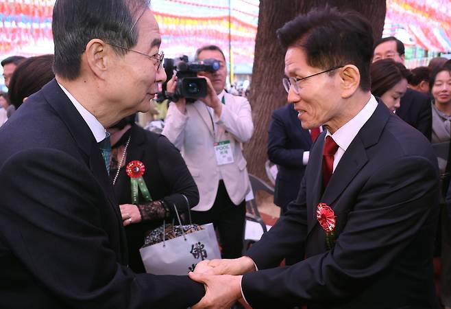 Former Prime Minister Han Duck-soo, left, and People Power Party presidential candidate Kim Moon-soo shake hands at an event for Buddha's Birthday at Jogye Temple in Jongno District, central Seoul, on May 5, 2025. [JOINT PRESS CORPS]