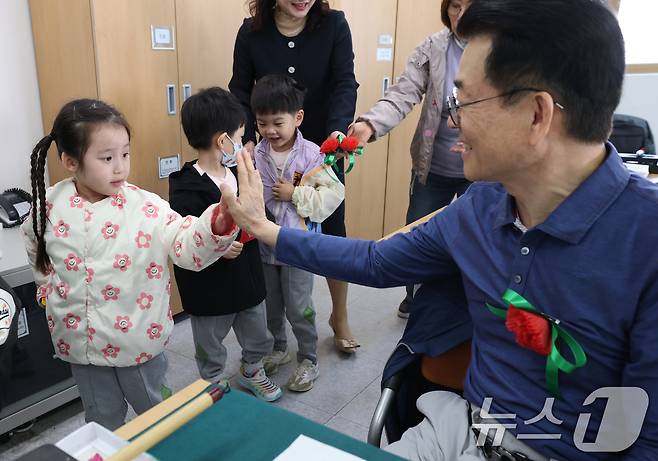 어버이날을 하루 앞둔 7일 오전 경기 수원시 팔달구 팔달노인복지관에서 관내 어린이집 아이들이 어르신들에게 카네이션을 달아드린 뒤 하이파이브을 하고 있다. 2025.5.7/뉴스1 ⓒ News1 김영운 기자