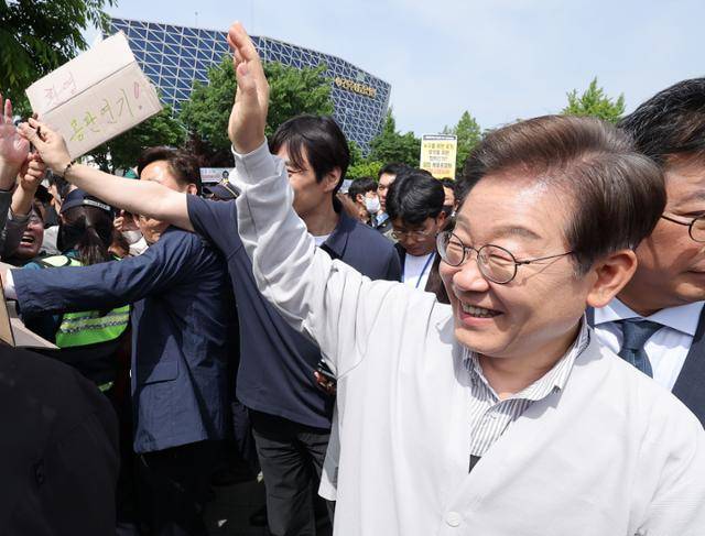 이재명 더불어민주당 대선 후보가 7일 전북 전주시 풍남문 앞 광장에서 지지자가 든 공판 연기 환영 팻말을 지나고 있다. 연합뉴스